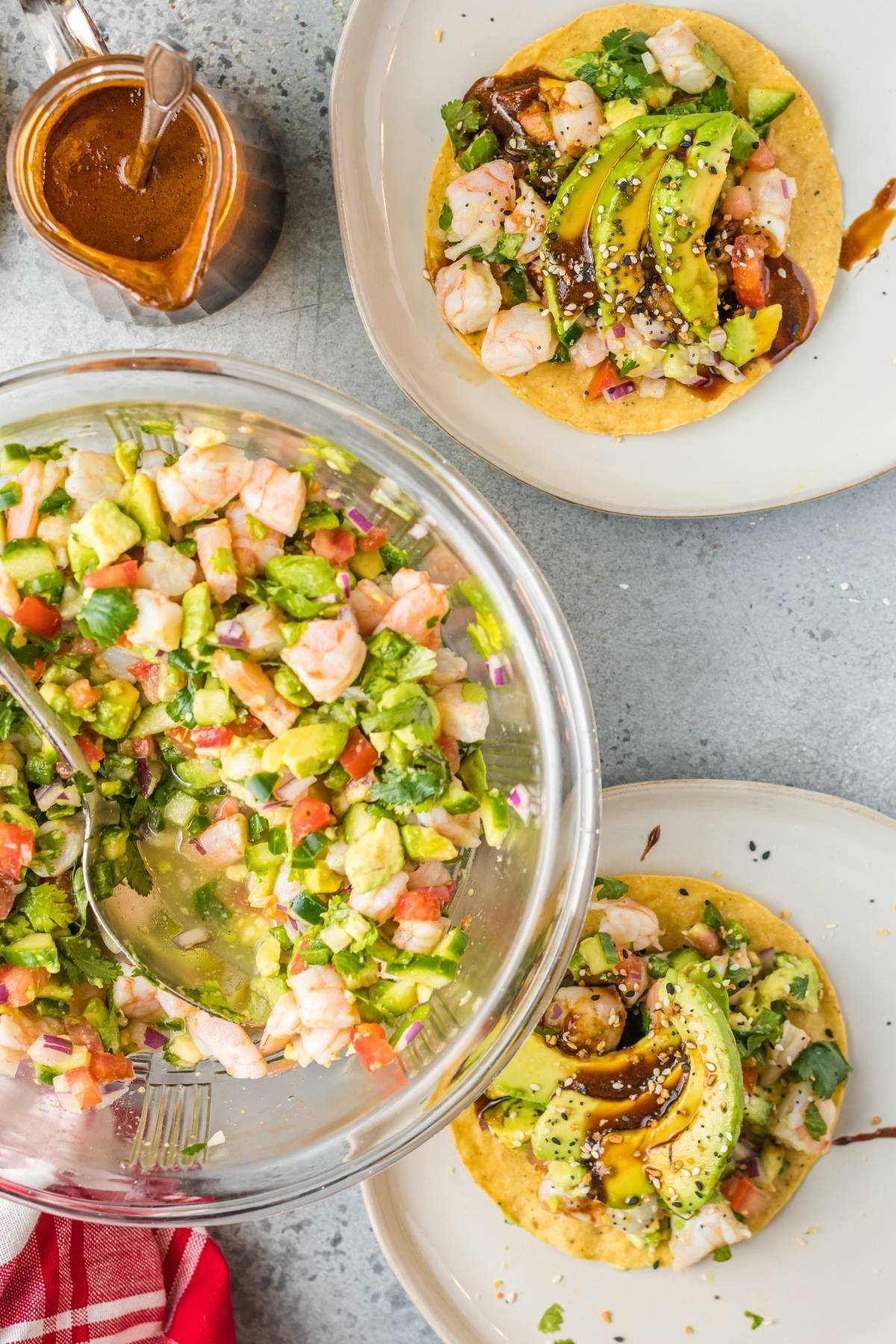 Overhead view of Mexican ceviche with fresh shrimp in a bowl and on tostadas, topped with avocado and sauce on plates.