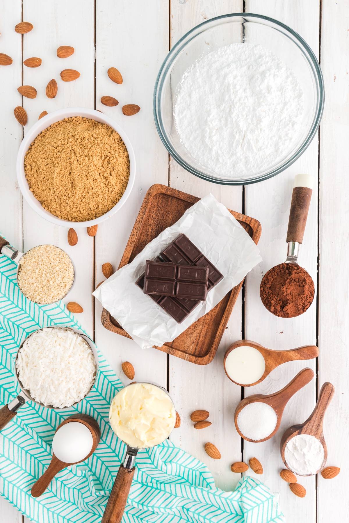 Baking ingredients on a white table, including chocolate, flour, sugar, butter, cocoa, eggs, and nuts—perfect for creating a classic Canadian dessert or an easy layered bar recipe.