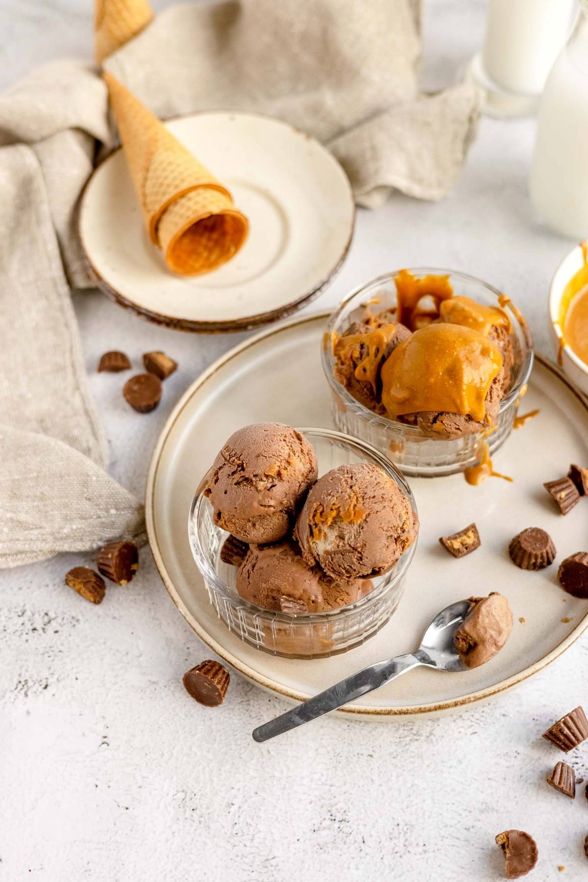 Indulge in no churn chocolate peanut butter cup ice cream, served in bowls with peanut butter swirls, mini peanut butter cups, and cones for the ultimate treat.
