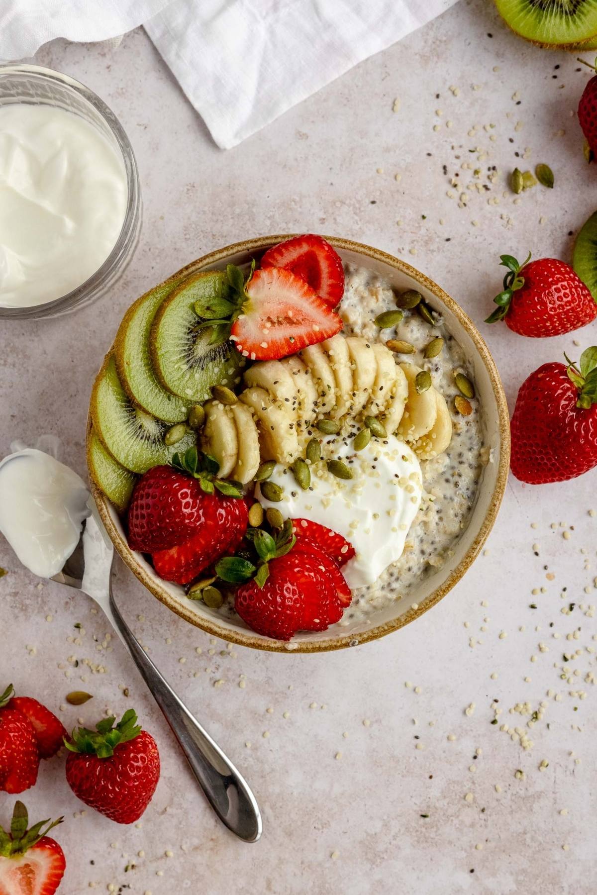 A bowl of chia pudding topped with sliced banana, kiwi, strawberries, seeds, and a dollop of yogurt makes a deliciously healthy oatmeal breakfast alternative to the classic Oatmeal Breakfast Bowl.