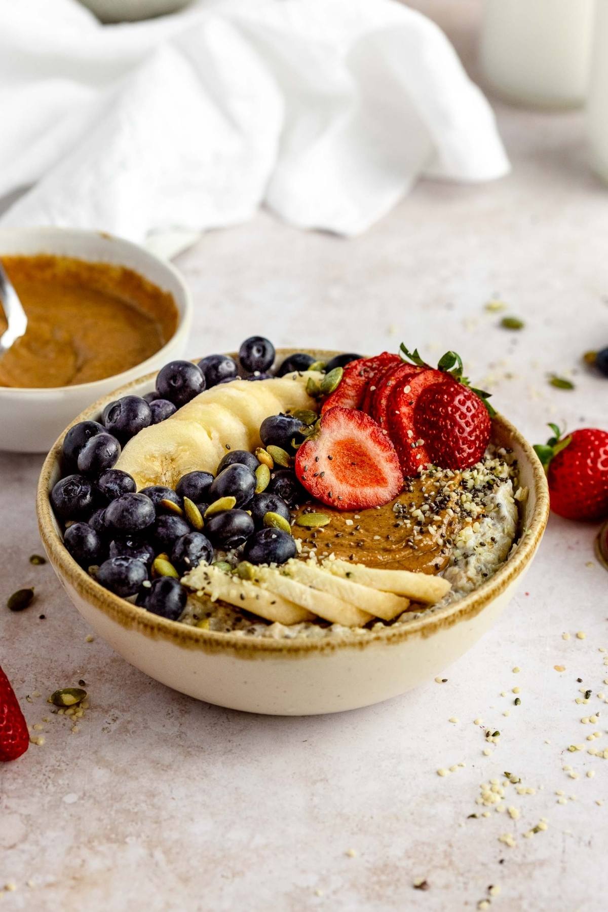 A healthy oatmeal breakfast featuring a bowl of oatmeal topped with blueberries, banana slices, strawberries, nuts, and seeds—discover delicious oatmeal bowl toppings to elevate your morning routine.