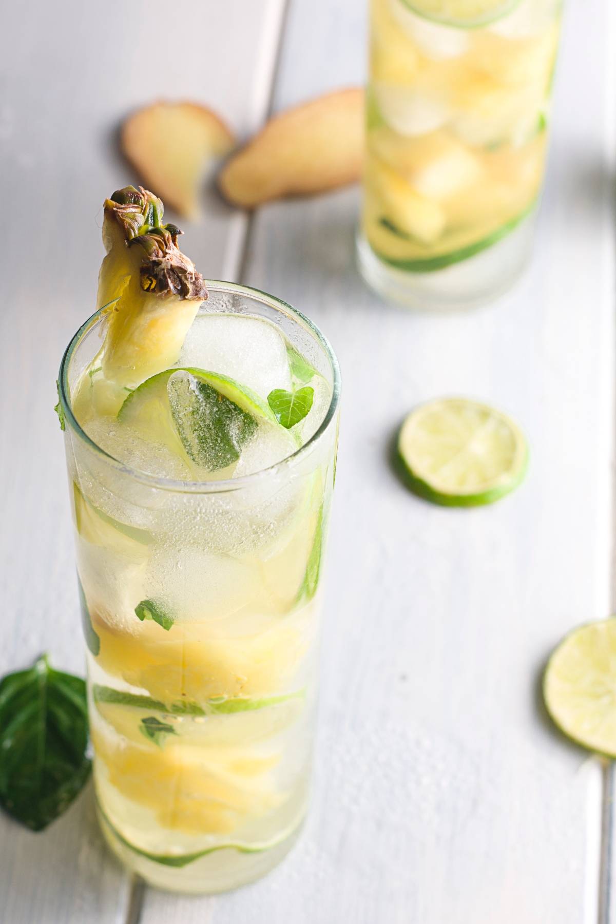 A tall glass of Easy Pineapple Mojito, garnished with pineapple and mint, sits on a light wooden table—refreshing tropical mocktail flavors in every sip.