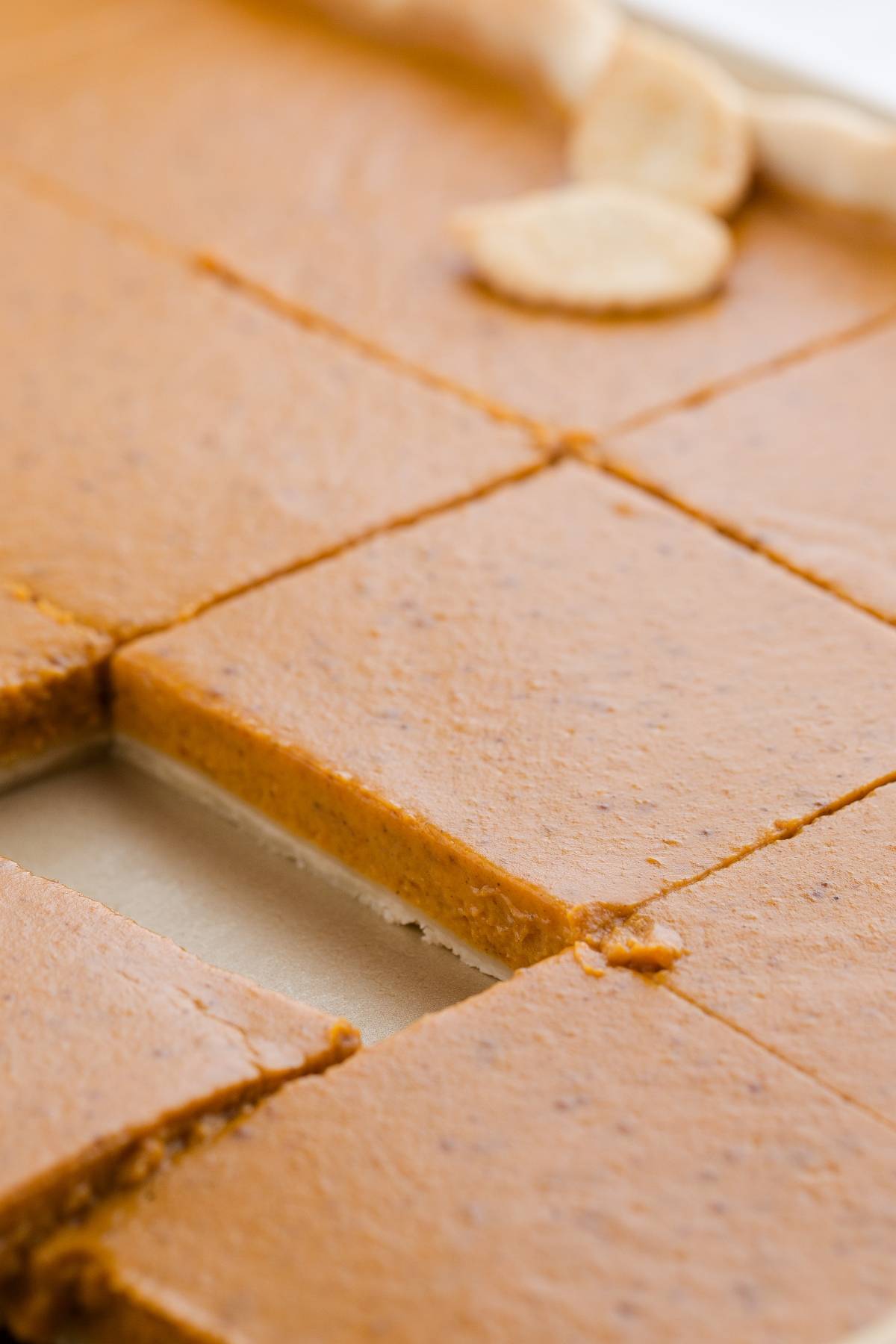 Close-up of sliced pumpkin pie bars, with one bar slightly lifted from the tray.