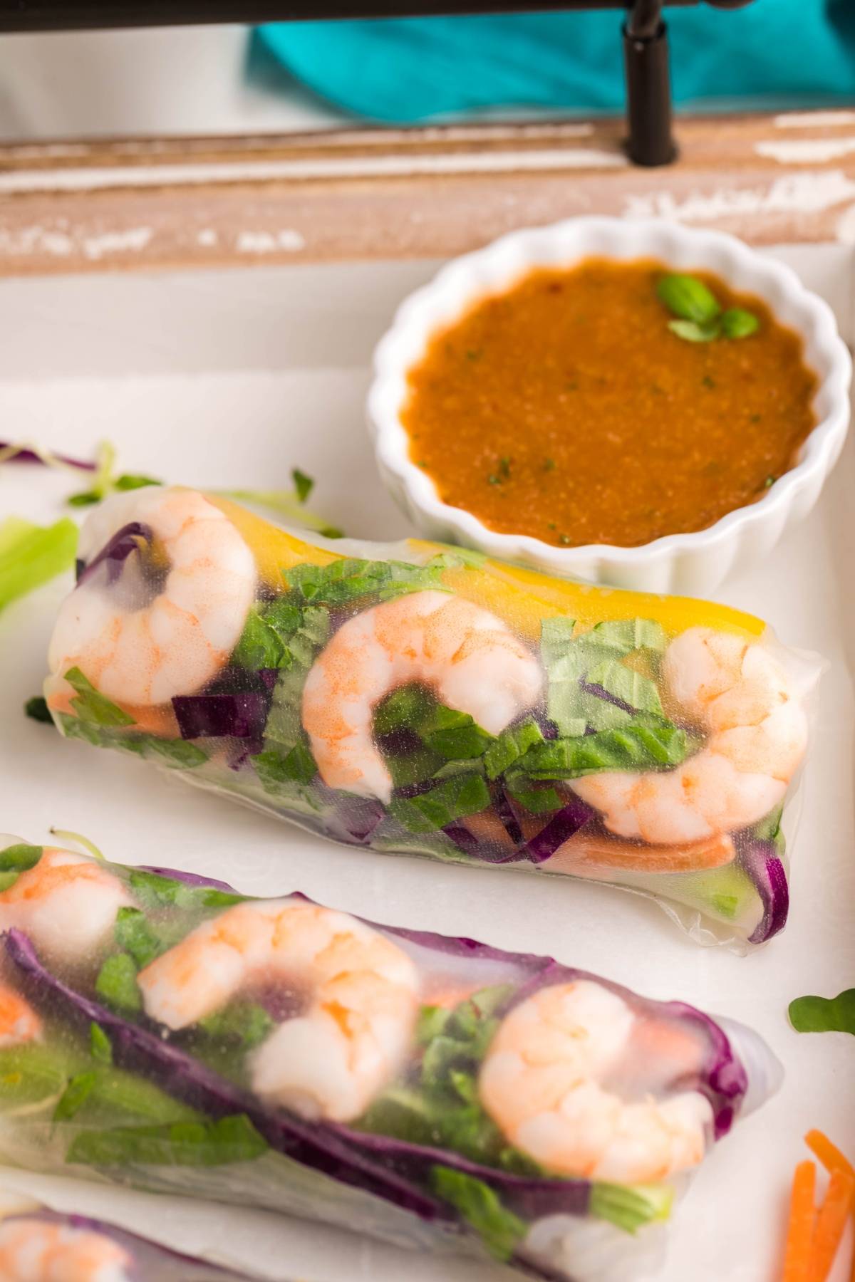 Fresh shrimp spring rolls with greens and purple cabbage, served with a small dish of spicy garlic sauce—the perfect dipping sauce for spring rolls.