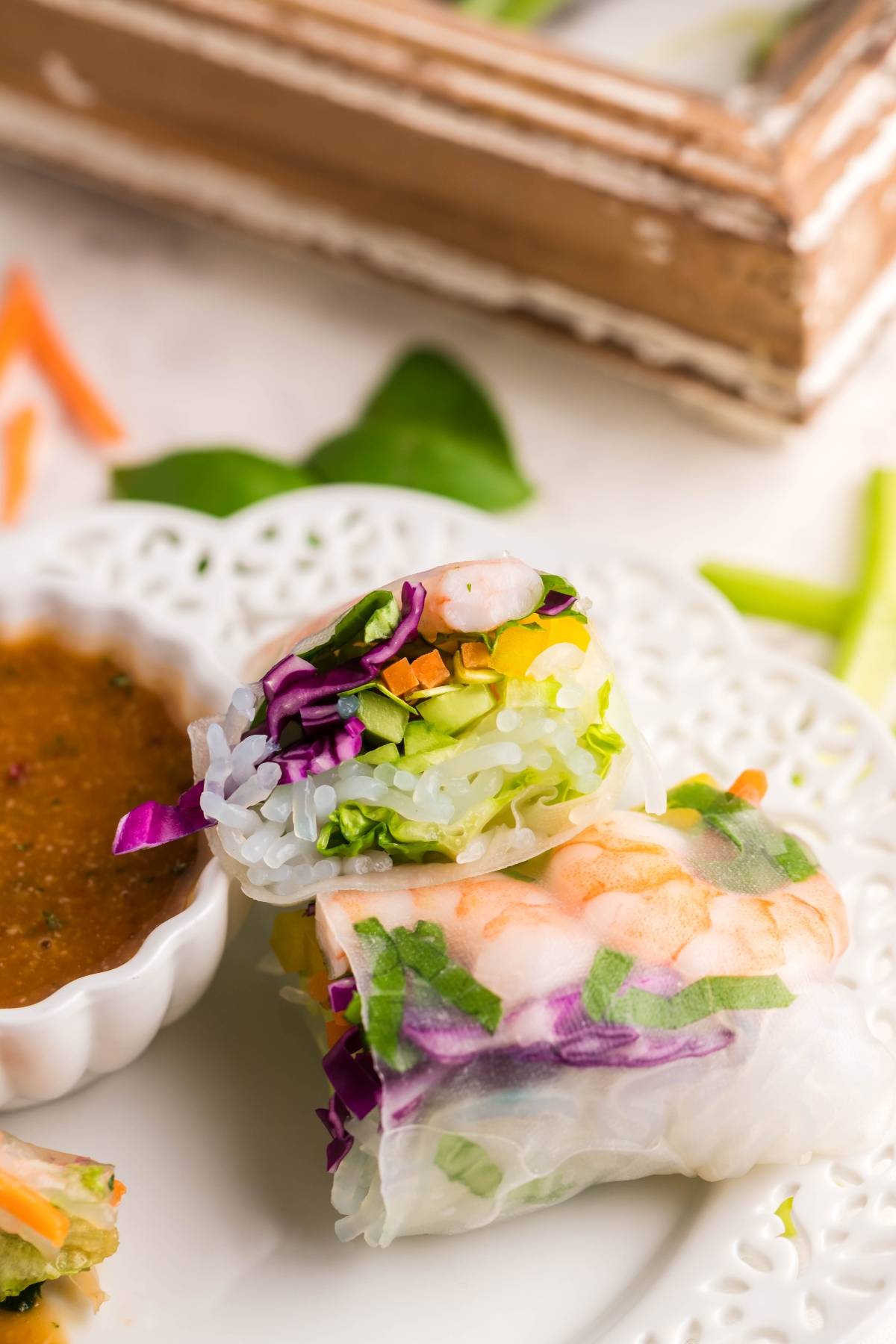 Fresh spring rolls filled with shrimp, noodles, and veggies, served with a spicy garlic sauce—the perfect dipping sauce for spring rolls—on a white plate.