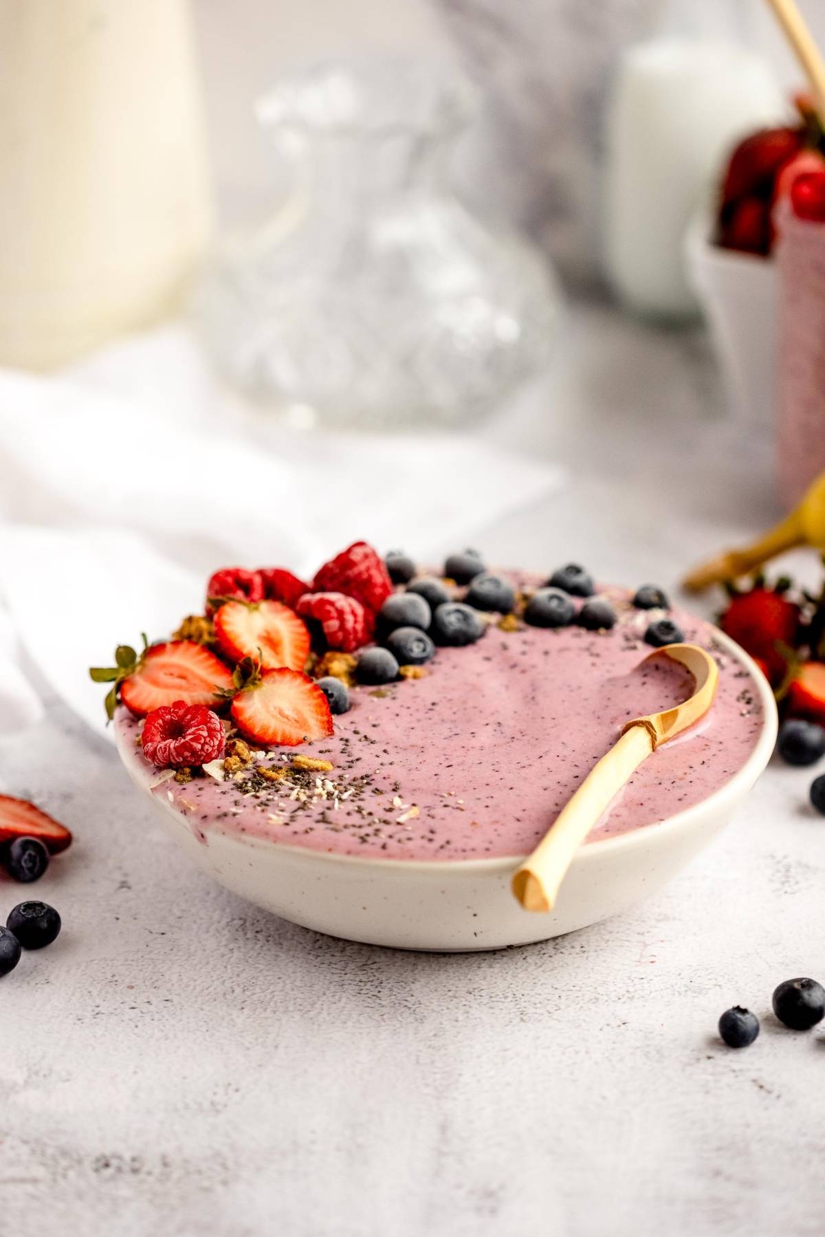 A smoothie bowl topped with strawberries, raspberries, blueberries, and chia seeds, served with a gold spoon—perfect for using your homemade smoothie pack for quick DIY Meal Prep.