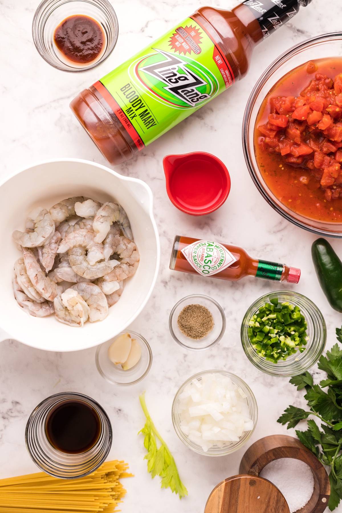Shrimp pasta with Bloody Mary vodka, diced tomatoes, Tabasco, and seasonings are artfully arranged on a marble surface for a spicy shrimp pasta bursting with flavor.
