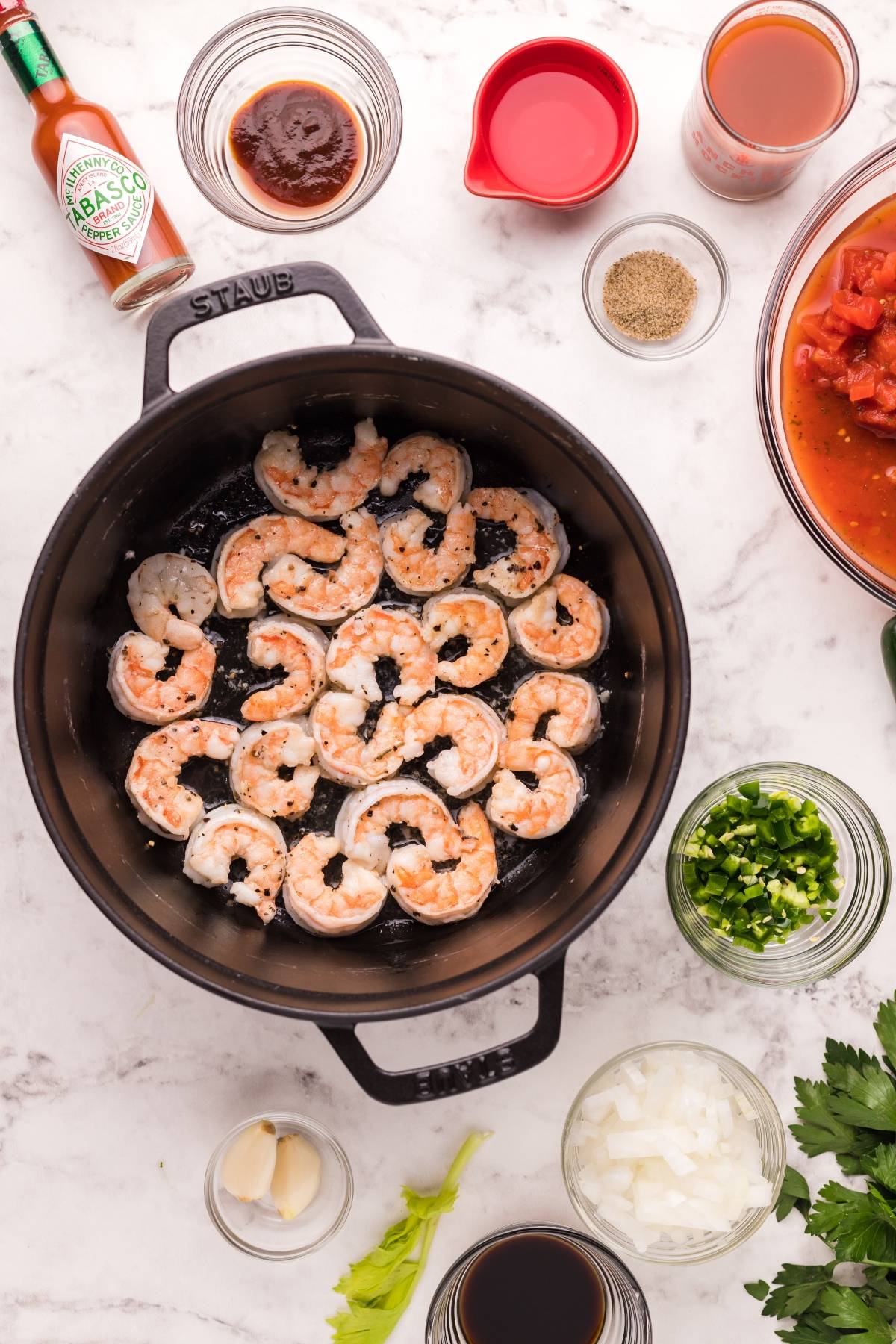 Shrimp cooking in a black pot, surrounded by bowls of chopped vegetables, sauces, and seasonings—perfect for preparing spicy shrimp pasta or a zesty shrimp pasta with Bloody Mary vodka.