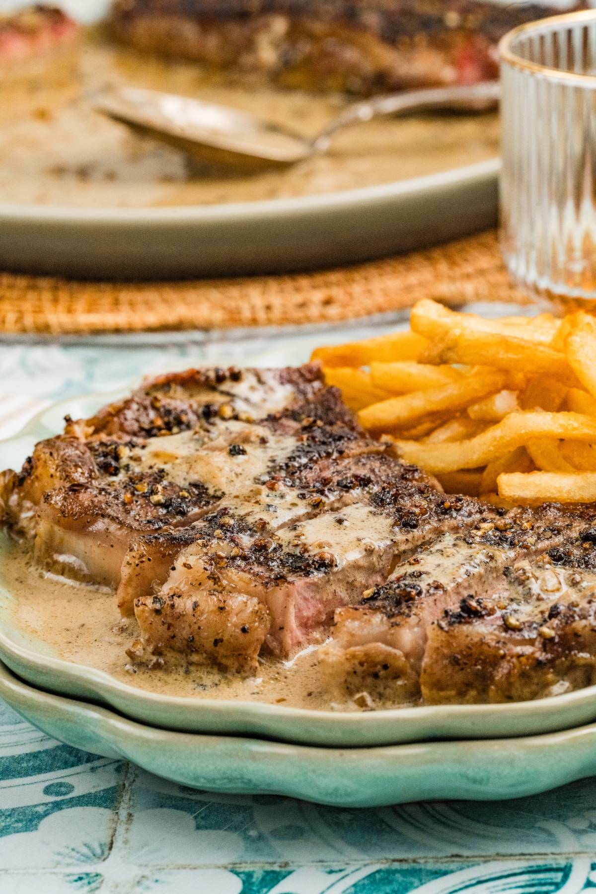Steak with creamy pepper sauce and a side of French fries on a plate.