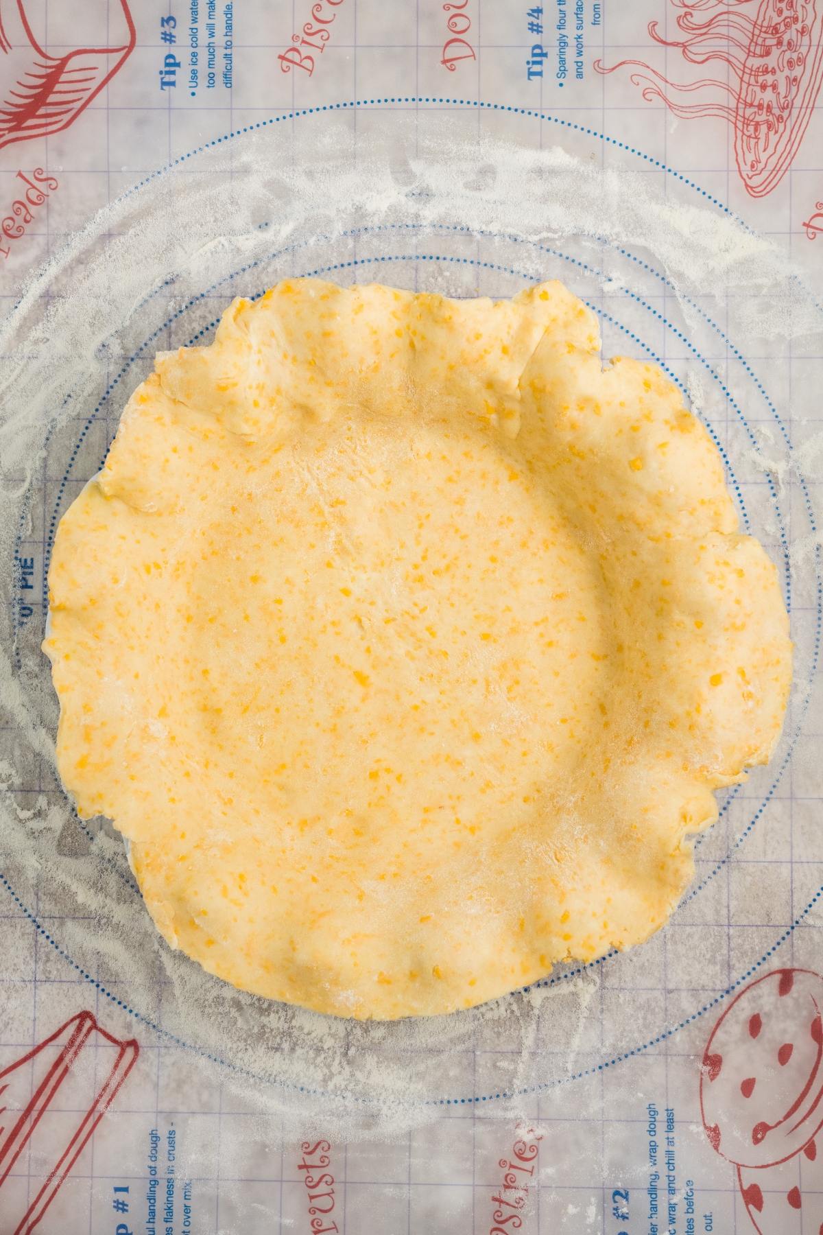 Unbaked pie crust pressed into a glass pie dish on a floured surface with baking illustrations.