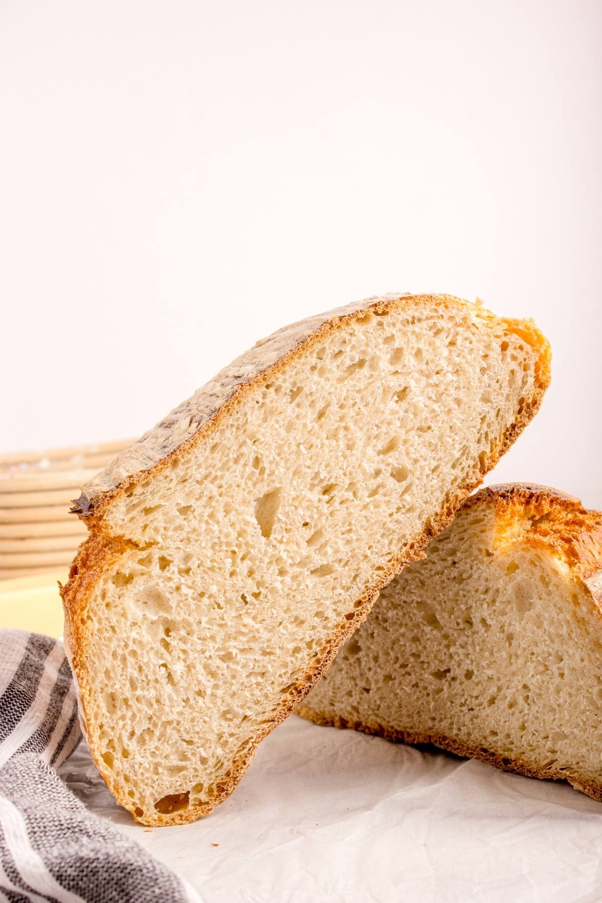 A sliced loaf of rustic bread with a golden crust and airy, light interior on a white surface.