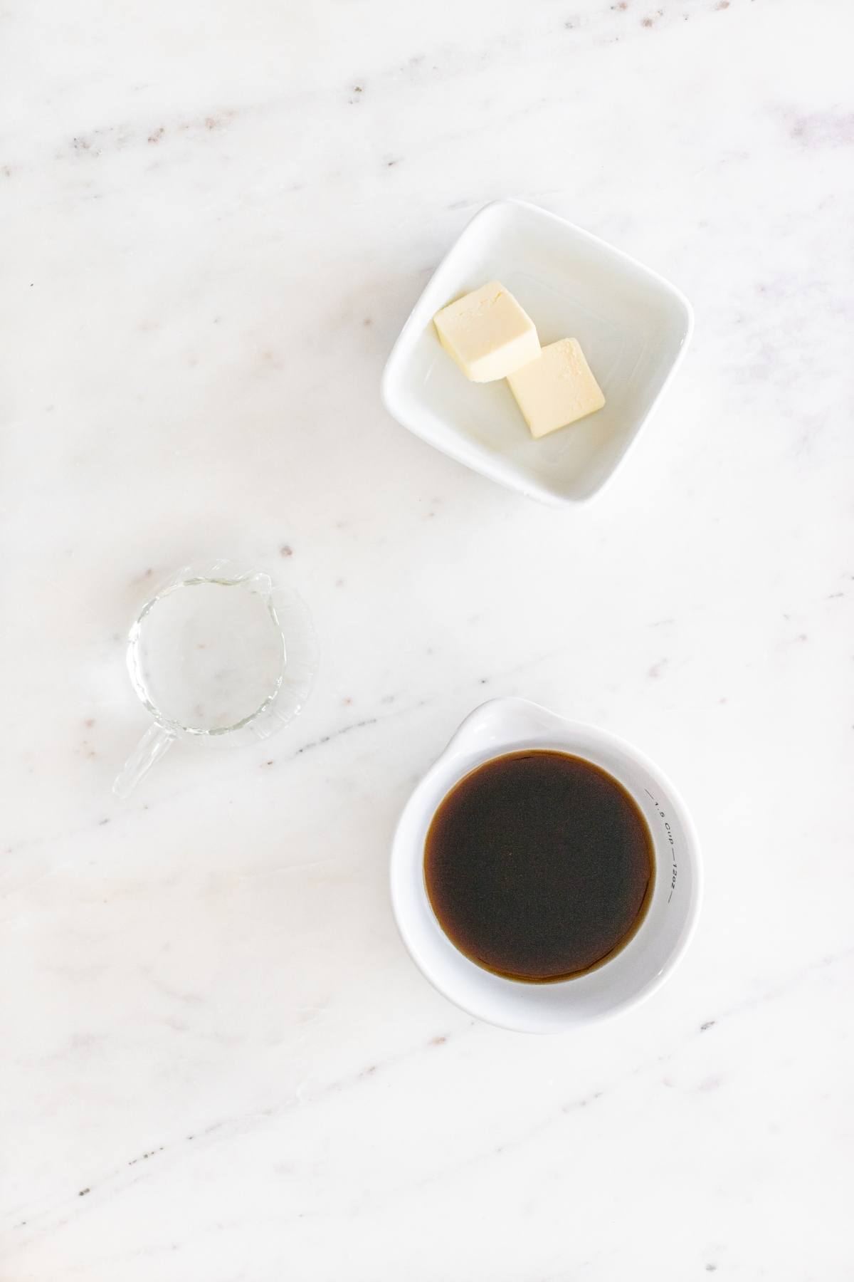 A bowl of liquid and butter on a marble table.