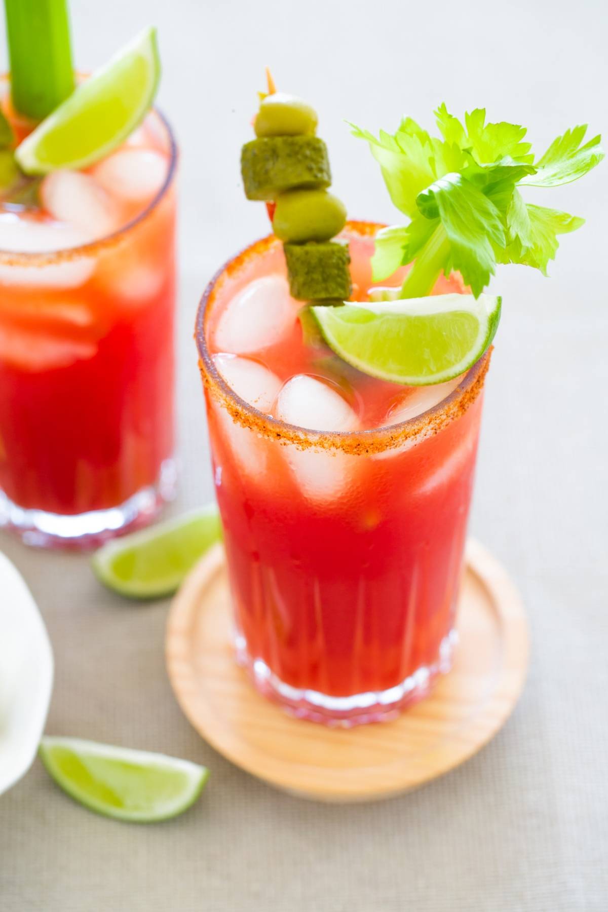 A Bloody Mary cocktail with Clamato juice, ice, lime wedge, celery stalk, and olives on a skewer in a glass—perfect as a classic Caesar cocktail for Canada Day celebrations.