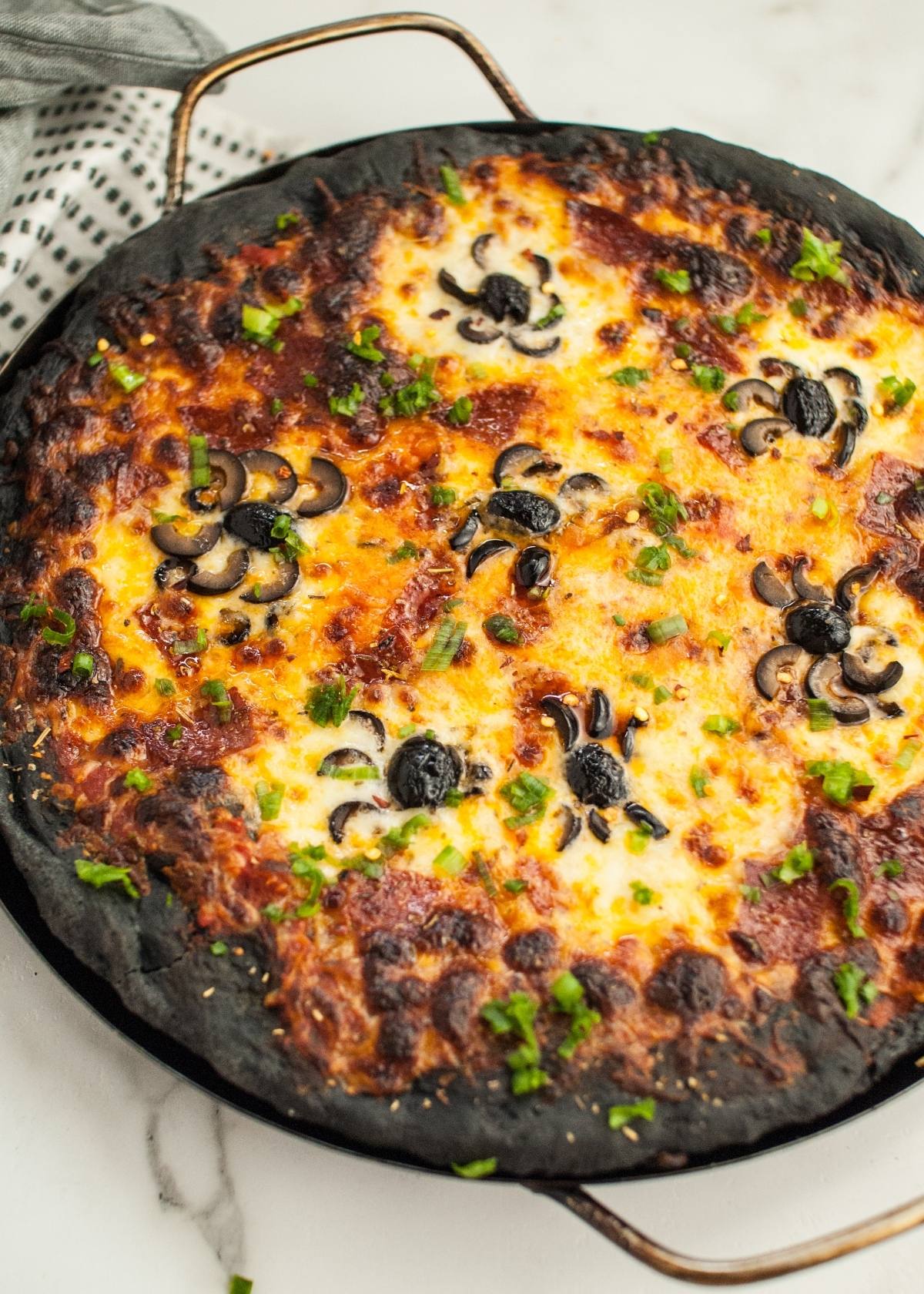 Halloween Pizza with Black Crust features charcoal pizza dough, melted cheese, and olive slices arranged like spiders—a spooky Halloween dinner menu for adults and kids alike.