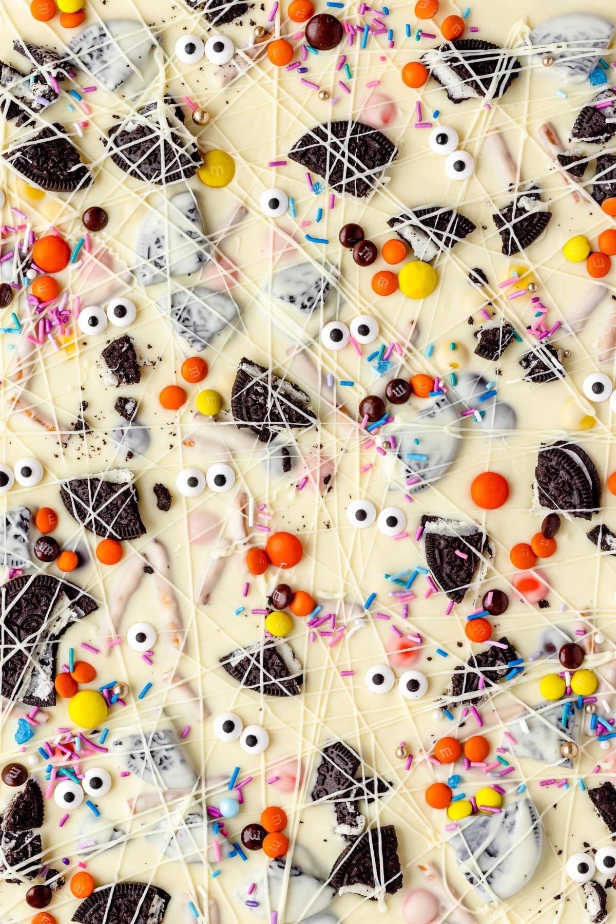 This Halloween treat with googly monster eyes features white chocolate bark topped with cookies, colorful candies, and sprinkles, then drizzled with white chocolate—a fun DIY Halloween candy!.