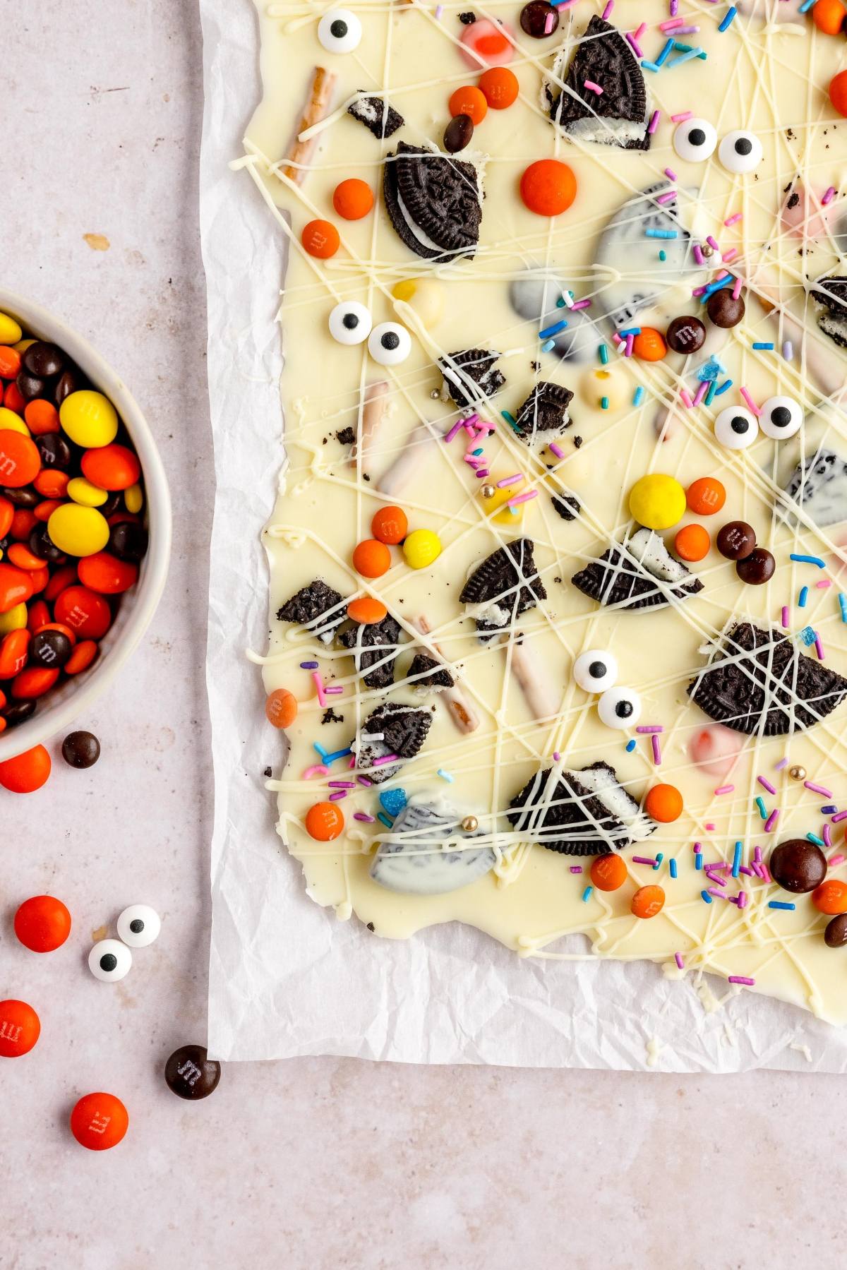 This Halloween White Chocolate Candy Bark is a festive Halloween treat with googly monster eyes, Oreos, Reese's Pieces, M&M's, and colorful sprinkles—perfect for your next halloween bark recipe!.