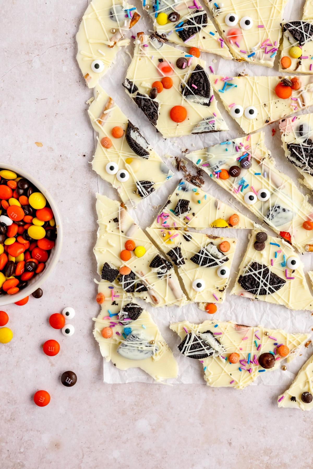 Halloween White Chocolate Candy Bark with candy eyes, sprinkles, and colorful candies is the perfect DIY Halloween candy. This fun halloween bark recipe is broken into festive pieces on parchment paper.