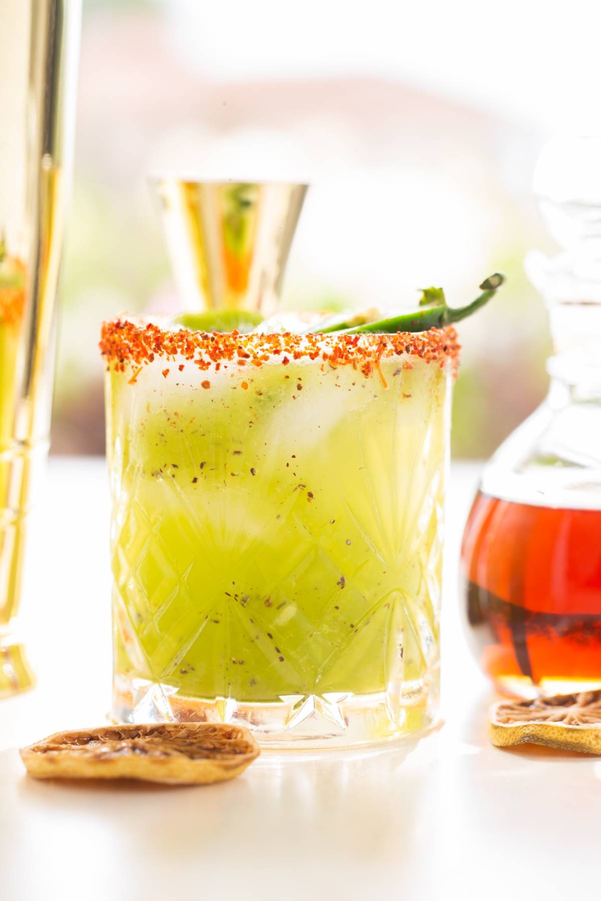 A cocktail using tequila and orange liqueur with a chili powder rim, vibrant green liquid, and a pepper garnish in a clear glass—perfect for those seeking the best spicy margarita experience.