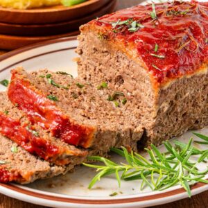 A sliced Lipton Meatloaf with tomato glaze on a plate, garnished with fresh rosemary.
