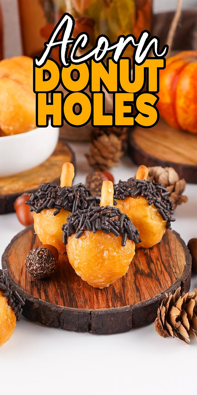 Three acorn donut holes, topped with chocolate sprinkles and pretzel stems, rest invitingly on a wooden platter.