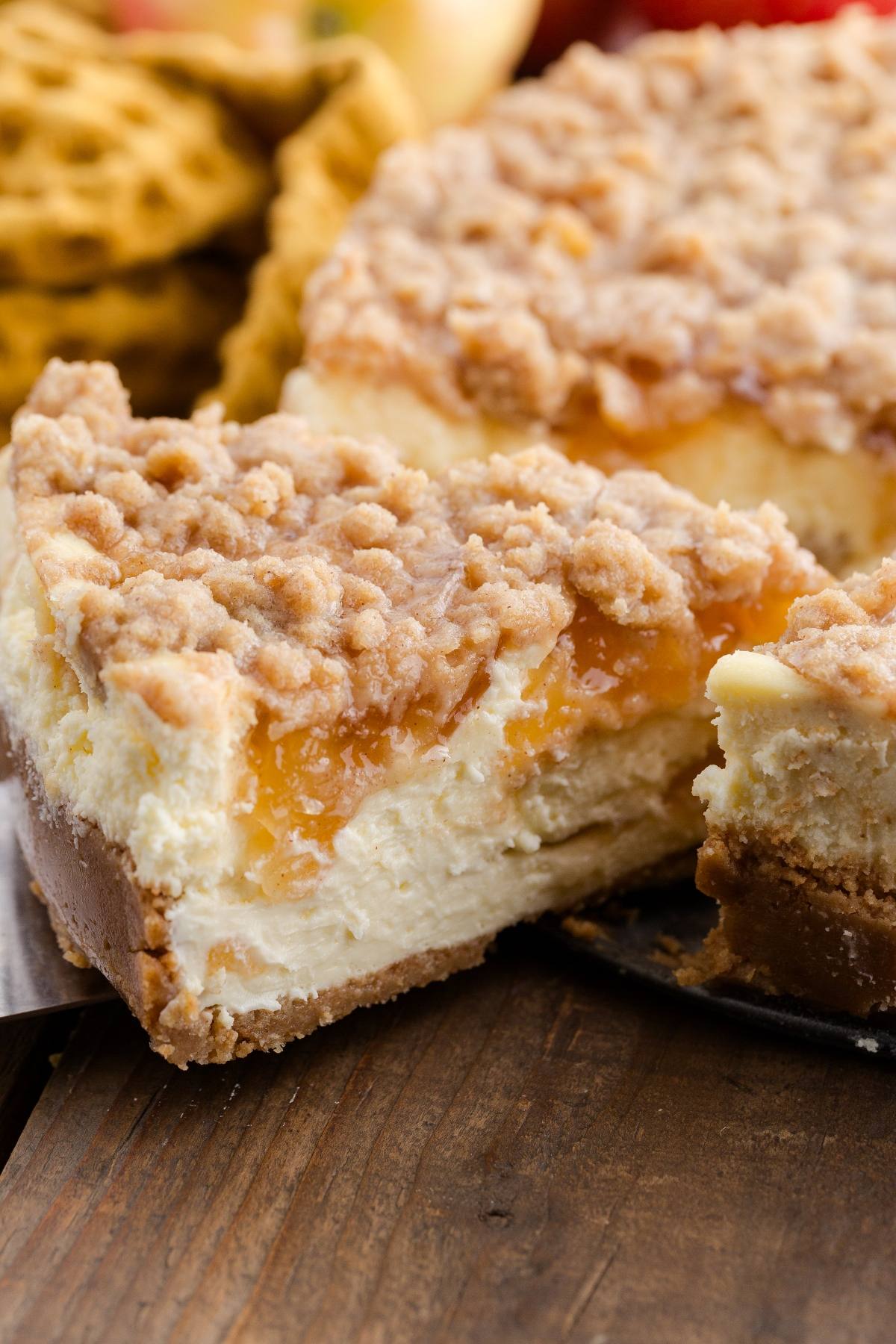 A close-up of a crumb-topped cheesecake with a slice cut out, showing creamy and crumbly layers.