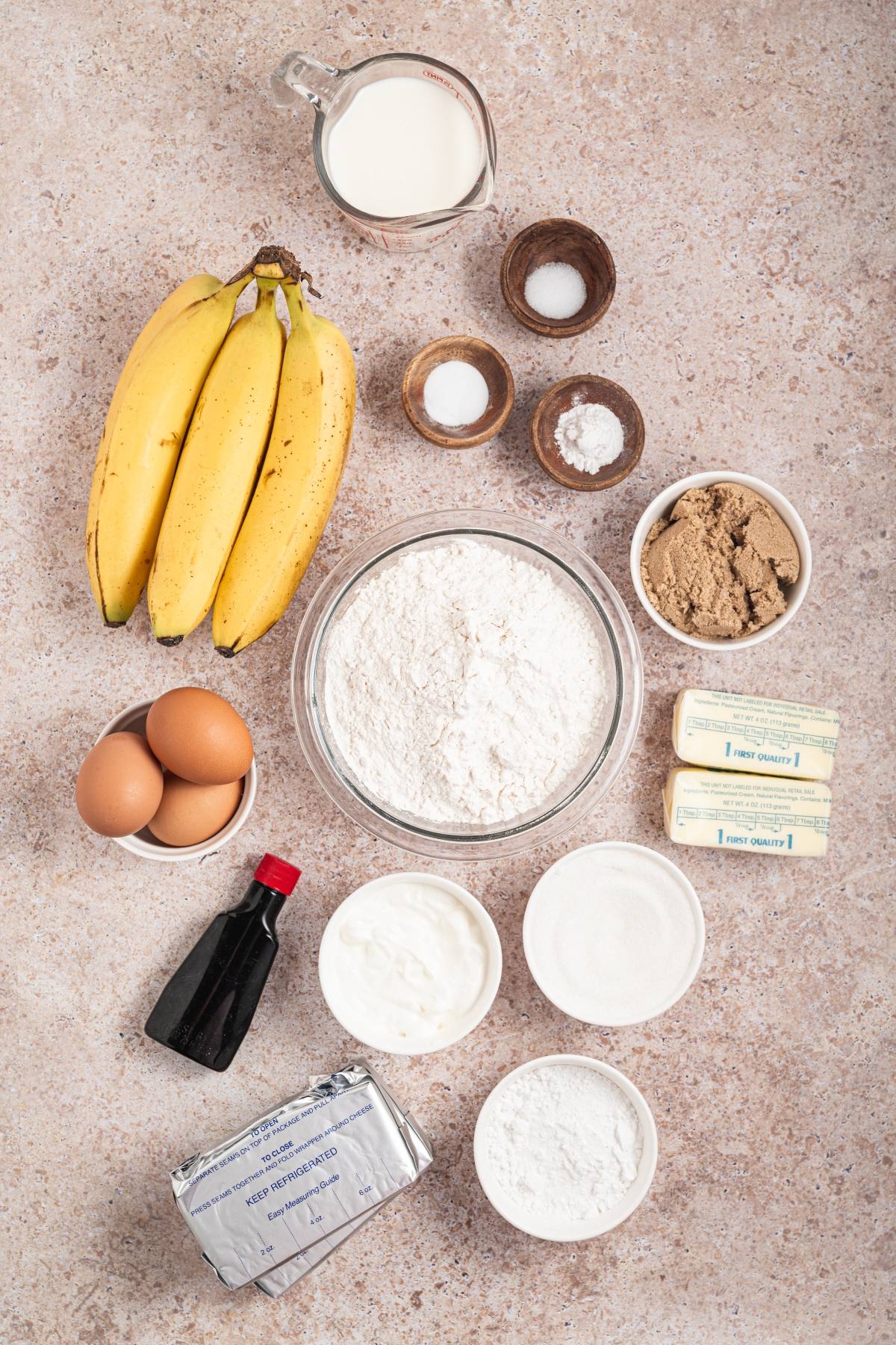 Ingredients for baking banana bread, including bananas, eggs, flour, sugar, butter, milk, and baking essentials.