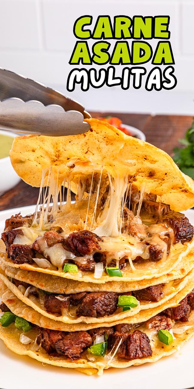Tongs lifting a cheesy carne asada mulita from a stacked plate, with gooey cheese stretching—perfect for carne asada mulitas lovers.