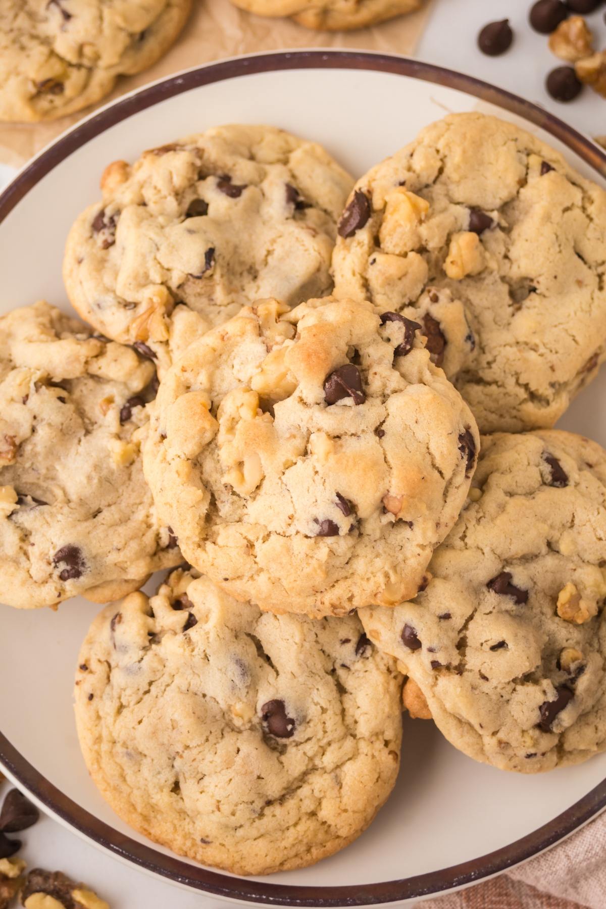 A plate of homemade chocolate chip cookies with walnuts, stacked closely together.