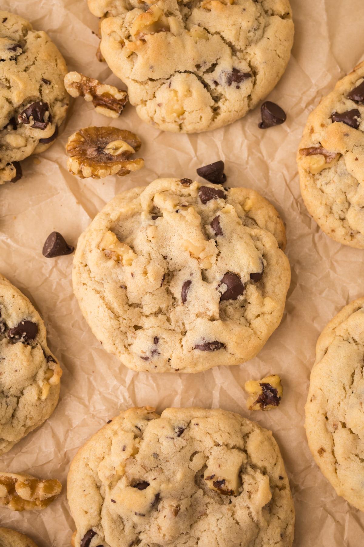 Chocolate chip cookies with walnuts on crinkled parchment paper, viewed from above.