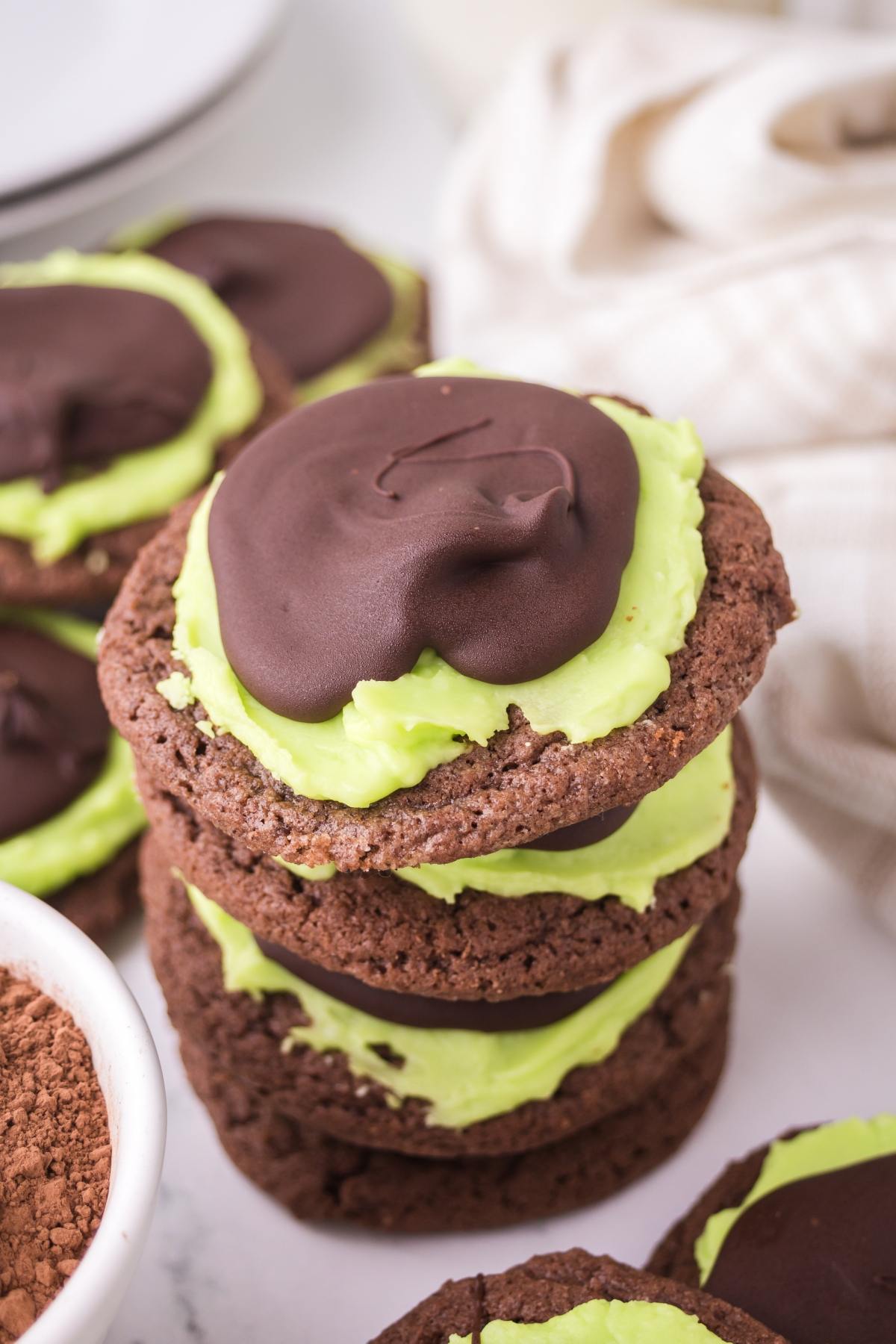 A stack of chocolate cookies with green frosting and a layer of chocolate on top.