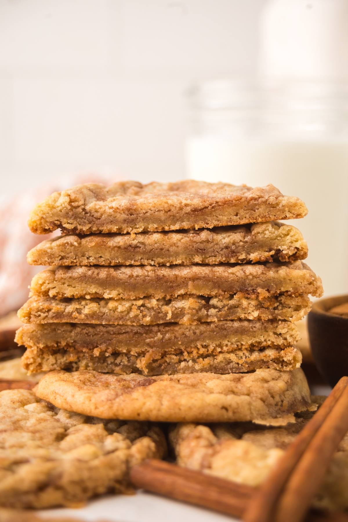 A stack of chewy brown sugar cookies with a glass of milk in the background.