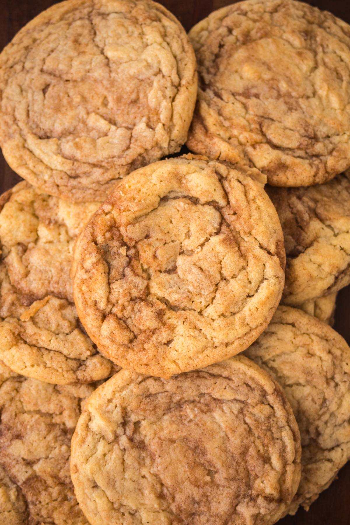 A close-up of several golden brown, chewy cinnamon sugar roll cookies stacked together.