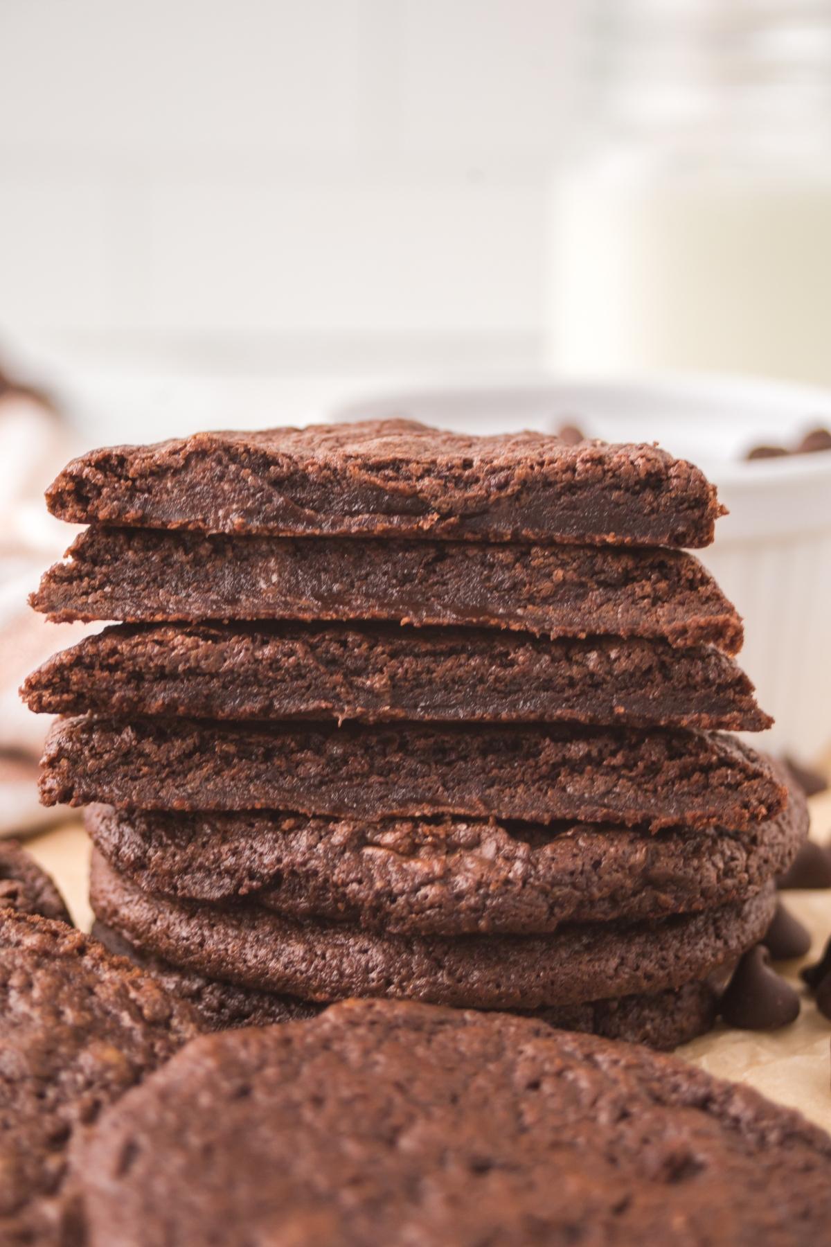 Stack of chewy double chocolate cookies with a glass of milk in the background.