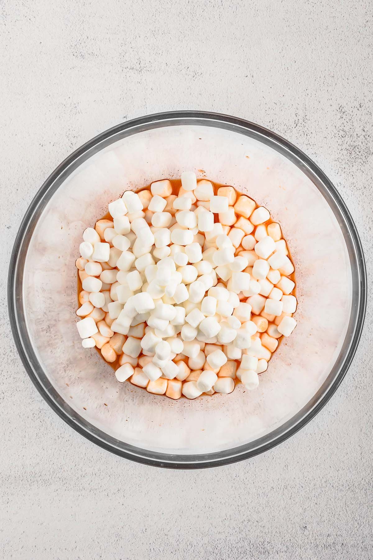 A glass bowl filled with mini marshmallows sits on a light-colored surface, perfect for adding a festive touch to your Halloween Jello Roll Ups.