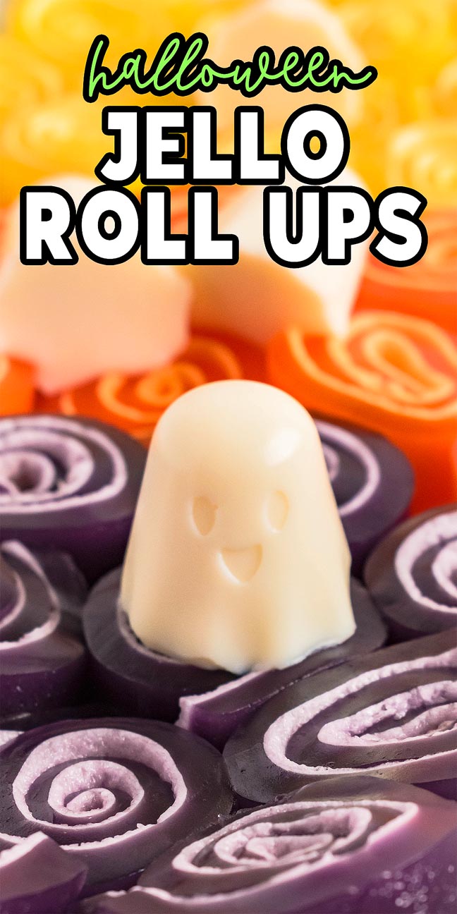A smiling white ghost-shaped jello sits among colorful Halloween Jello Roll Ups in vibrant purple and orange hues.