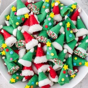 A bowl of festive red and green Christmas Bugles elf hat treats decorated with sprinkles, stars, and white icing.