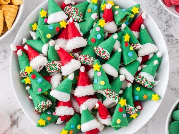 A bowl of festive red and green Christmas Bugles elf hat treats decorated with sprinkles, stars, and white icing.