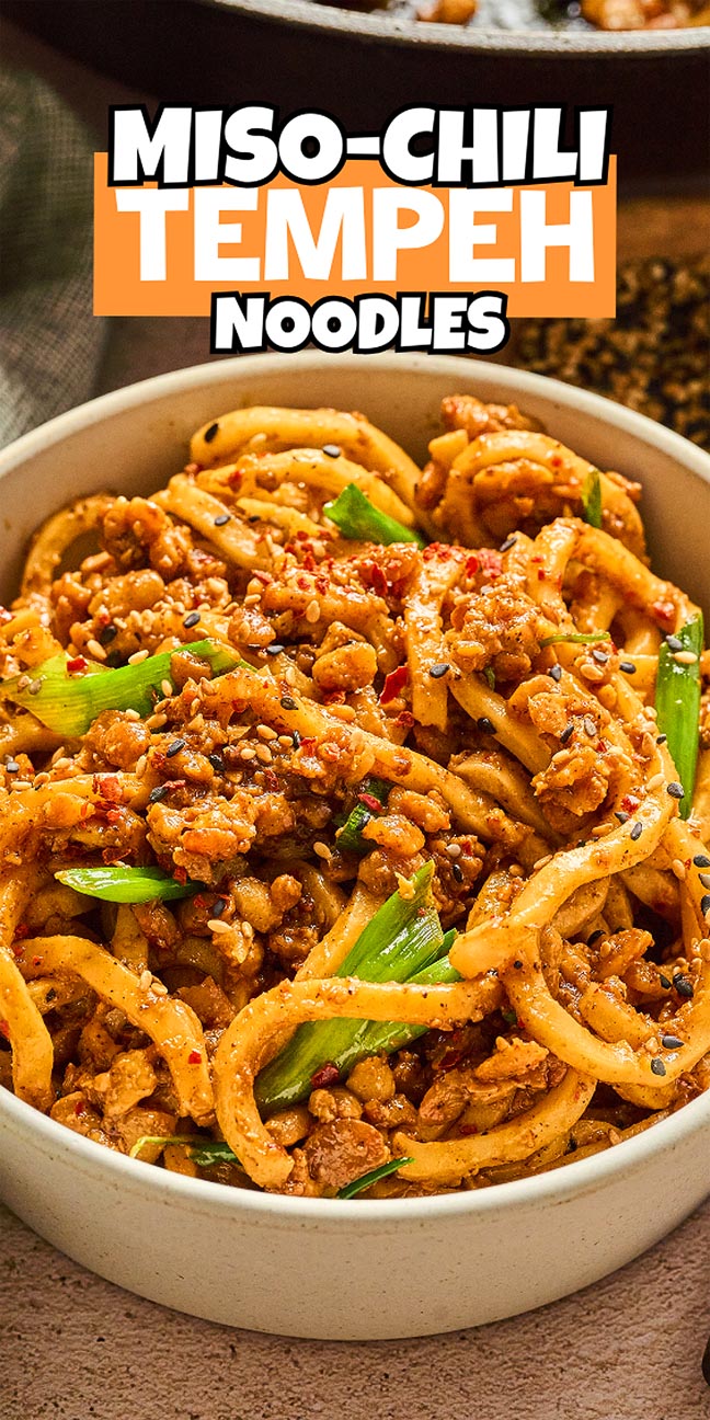 A bowl of Miso-Chili Tempeh Noodles garnished with green onions and chili flakes.