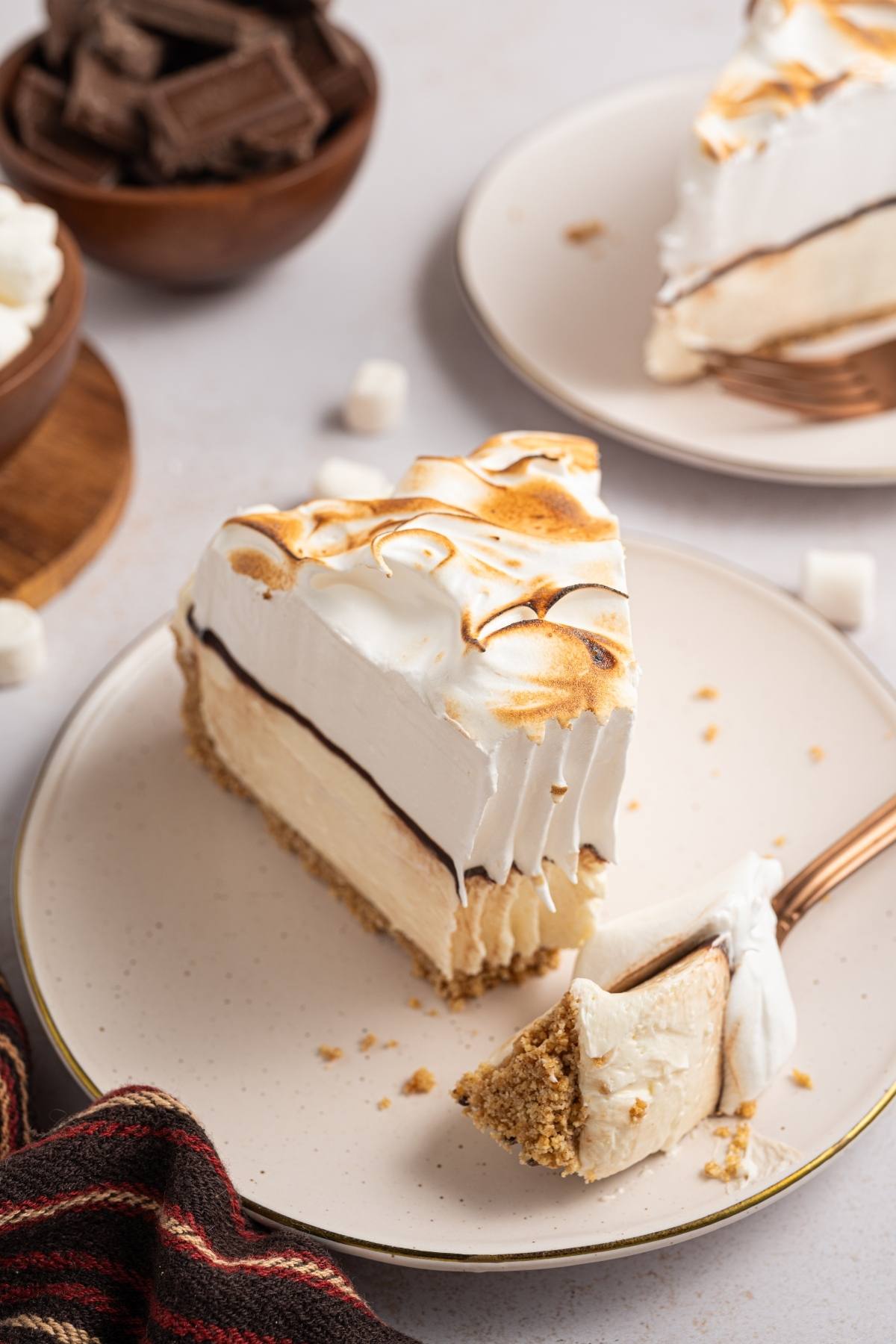 A slice of pie with toasted meringue topping on a plate, with a forkful taken out.