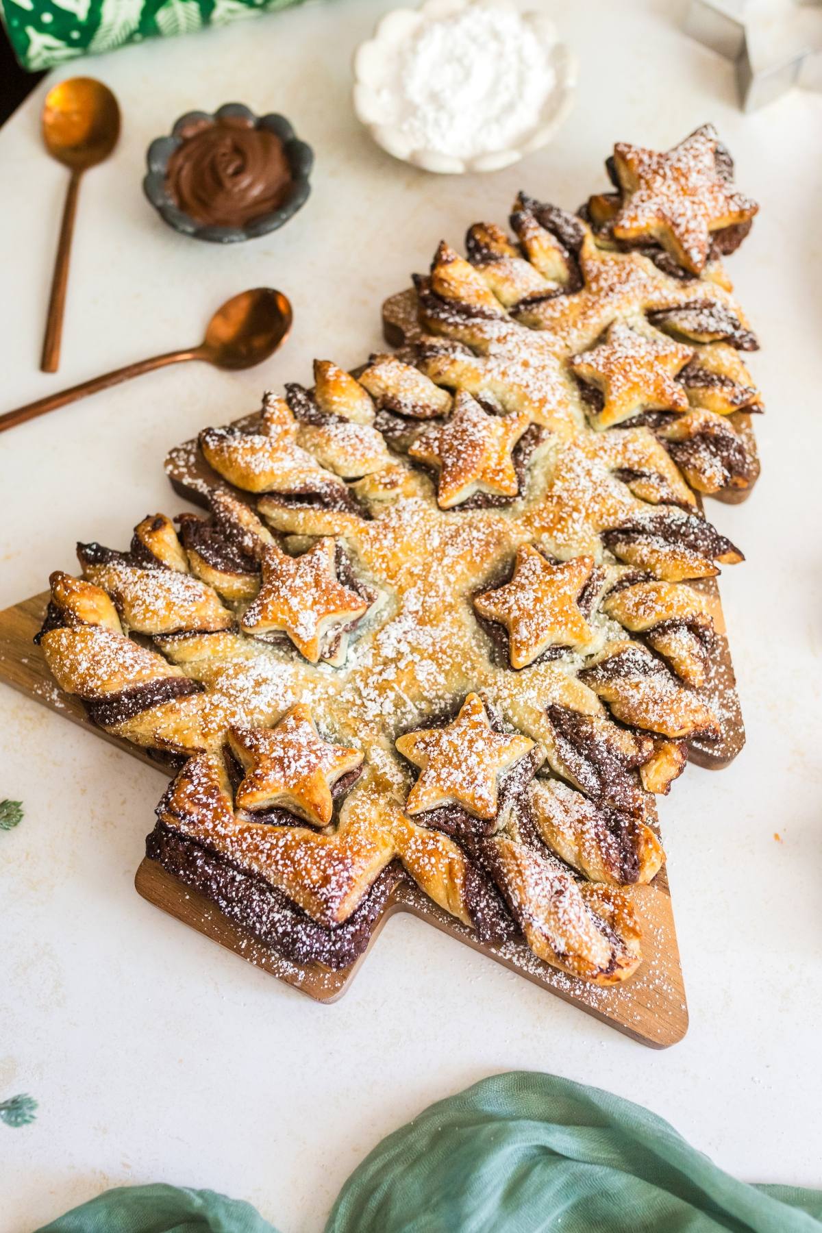 A Christmas tree-shaped pastry with chocolate filling, decorated with powdered sugar and star-shaped pieces.
