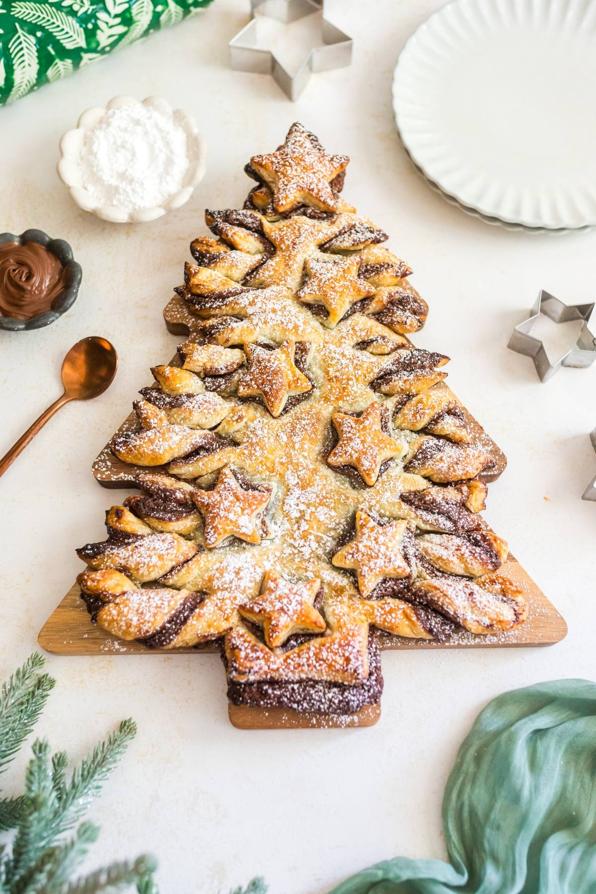 A Christmas tree-shaped pastry dusted with powdered sugar, decorated with star-shaped pieces.