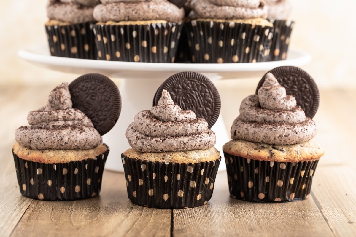 Three Oreo cupcakes with cookies and cream frosting and chocolate sandwich cookie toppers, served in polka dot wrappers.
