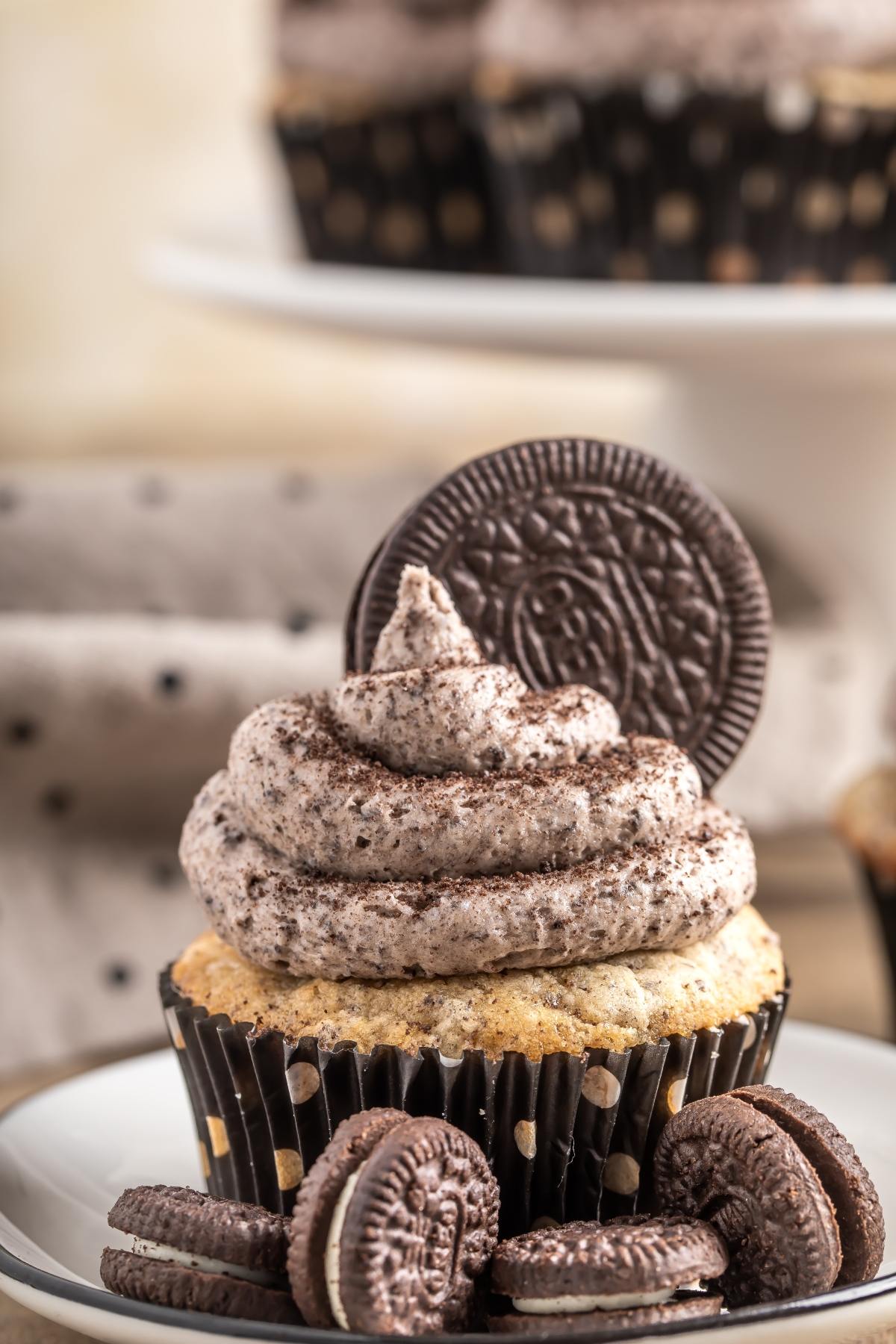 A cupcake with cookies-and-cream frosting, topped with a chocolate cookie and surrounded by mini cookies.