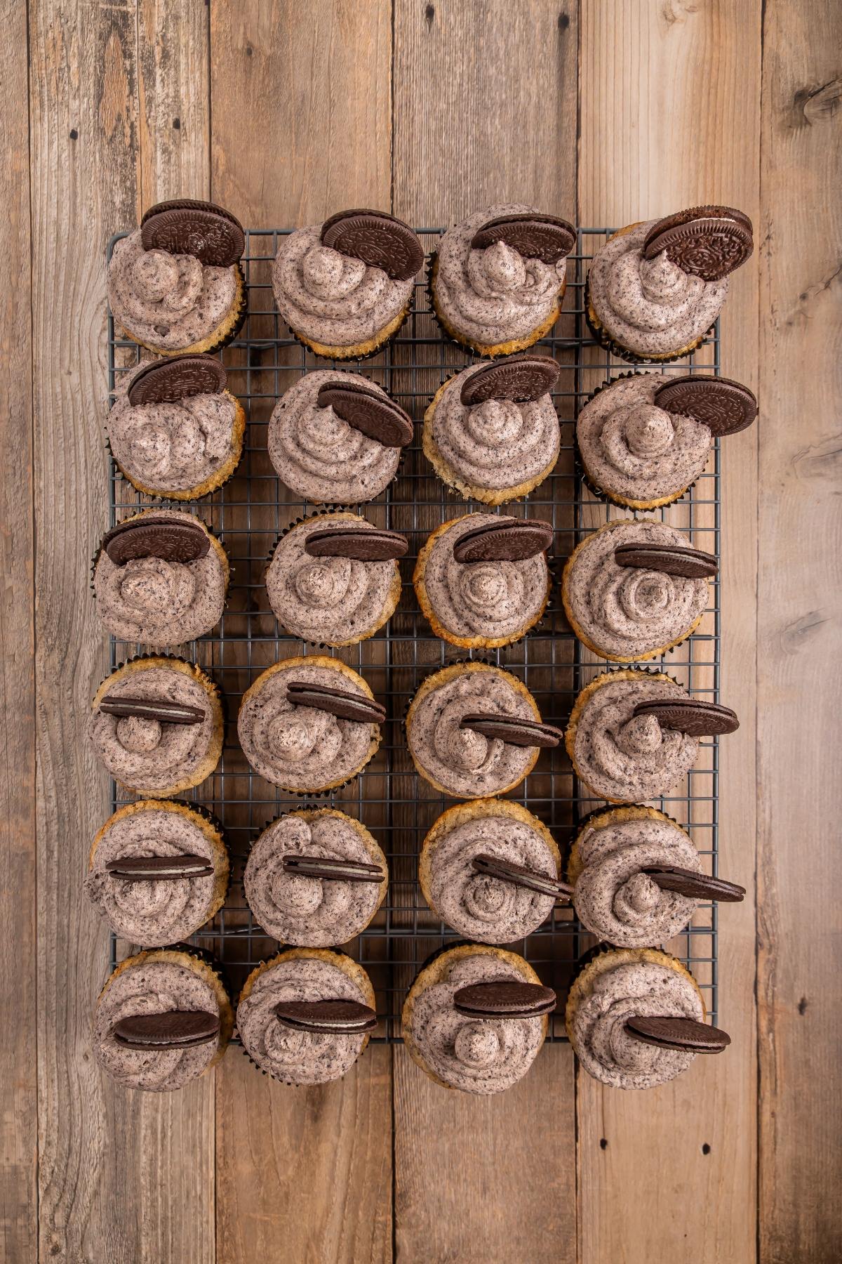 Cookies and cream cupcakes with swirled frosting and cookie halves on a cooling rack, top view.