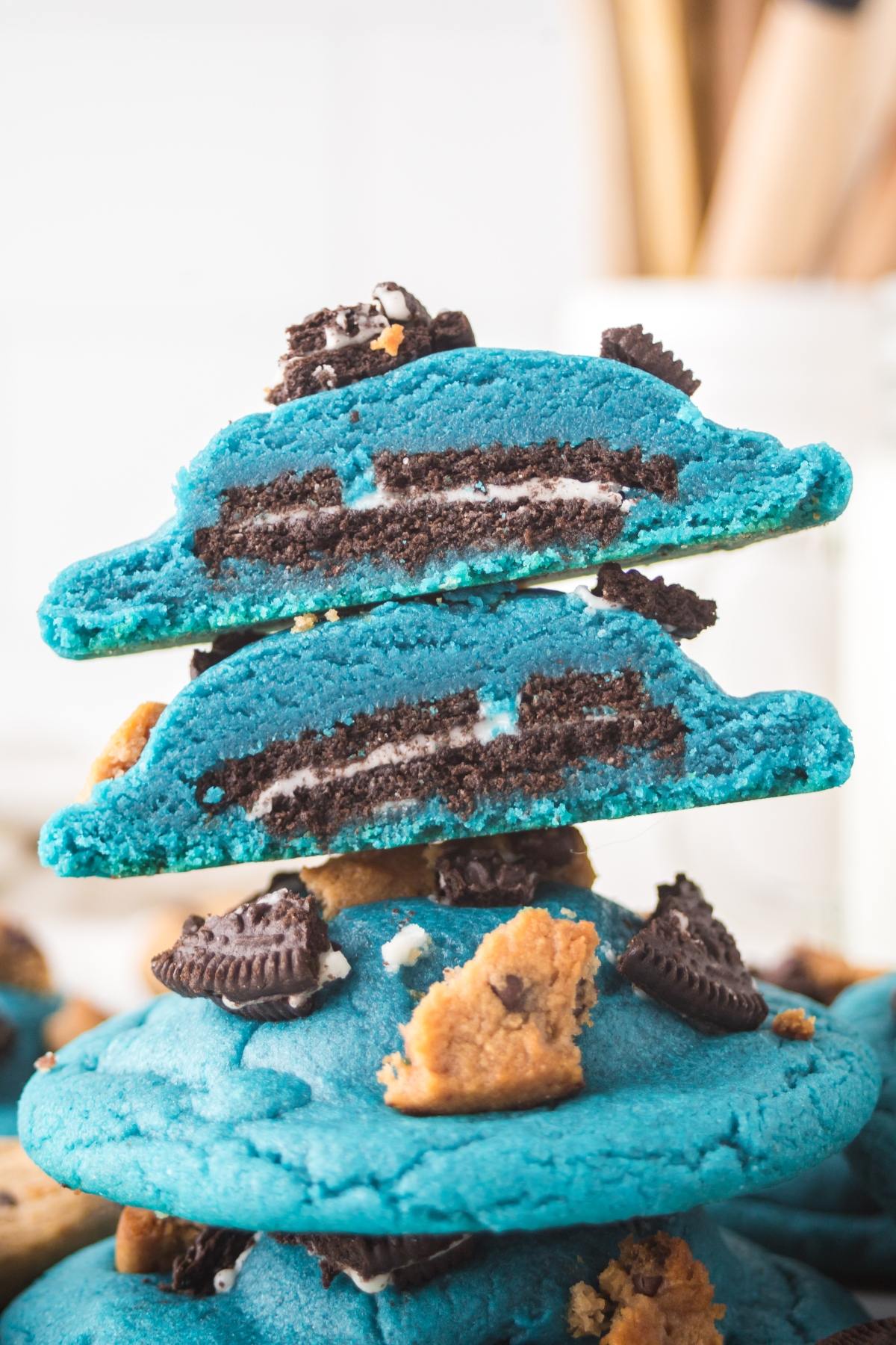 Blue cookies with Oreo and chocolate chip cookie pieces inside and on top, stacked in a close-up view.