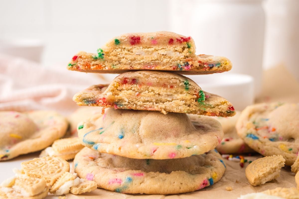 Stack of Oreo Stuffed Funfetti Cookies with colorful sprinkles, some broken in half to reveal their soft, chewy inside and a delicious Oreo surprise at the center.