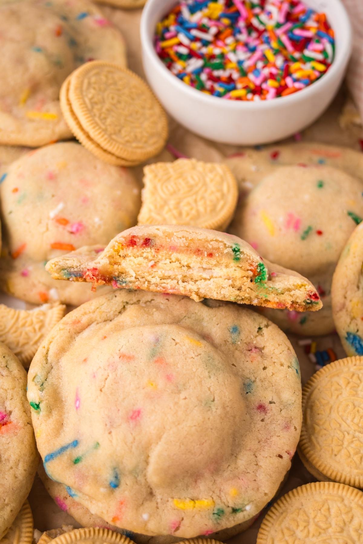 Funfetti cookies with golden sandwich cookie centers, surrounded by colorful sprinkles and more cookies.