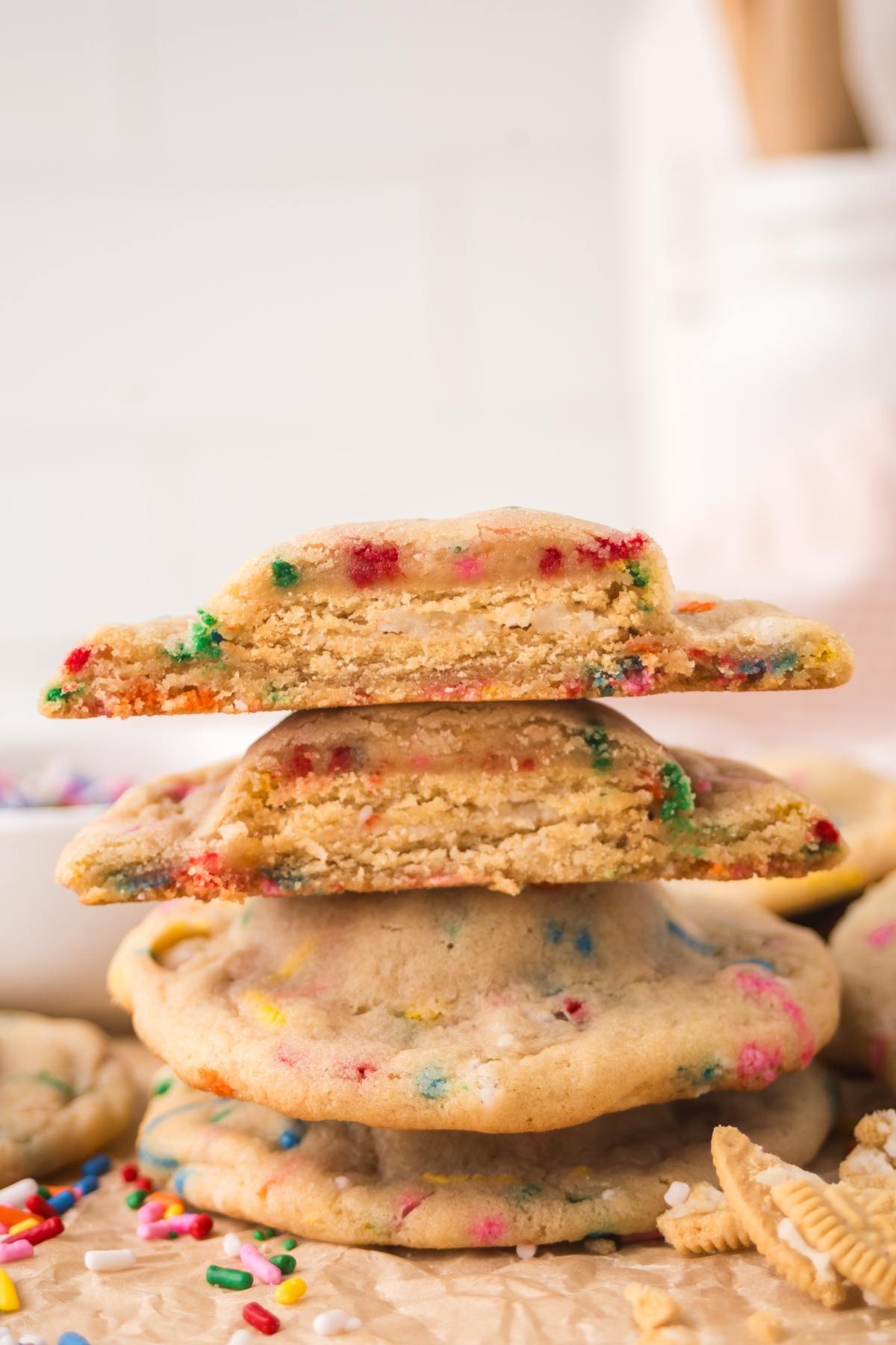 A stack of colorful funfetti cookies, with two halves showing a soft, chewy interior.