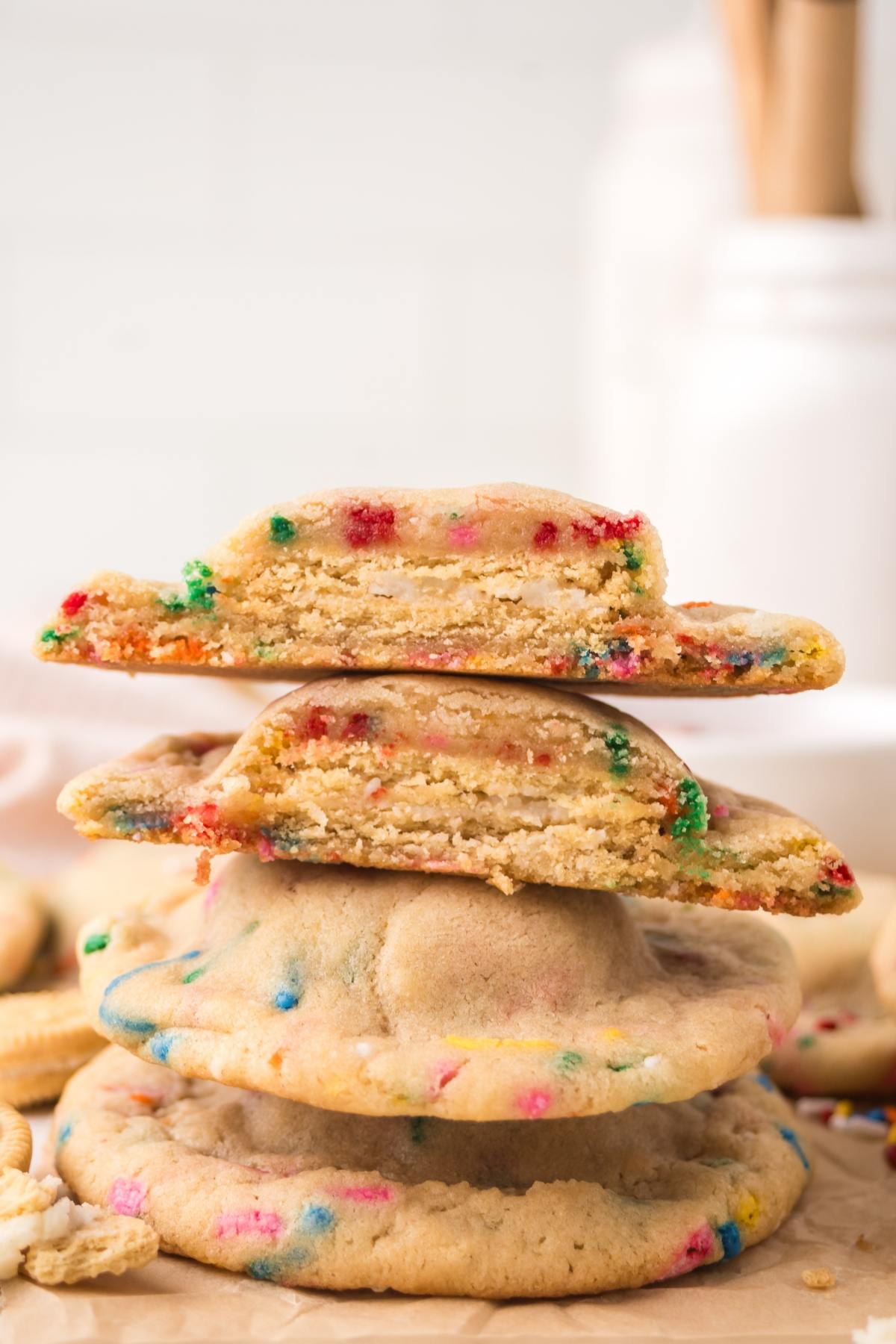 A stack of colorful funfetti cookies, with two halves showing a soft, chewy inside.