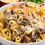 A bowl of rigatoni pasta alla Genovese, topped with tender shredded meat and grated cheese.